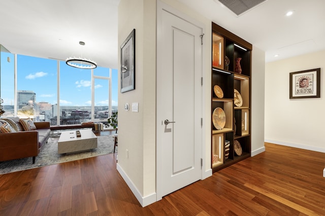 hall featuring a notable chandelier, expansive windows, and dark wood-type flooring