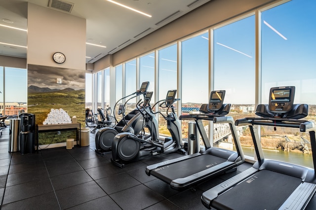 gym featuring dark tile flooring and a water view