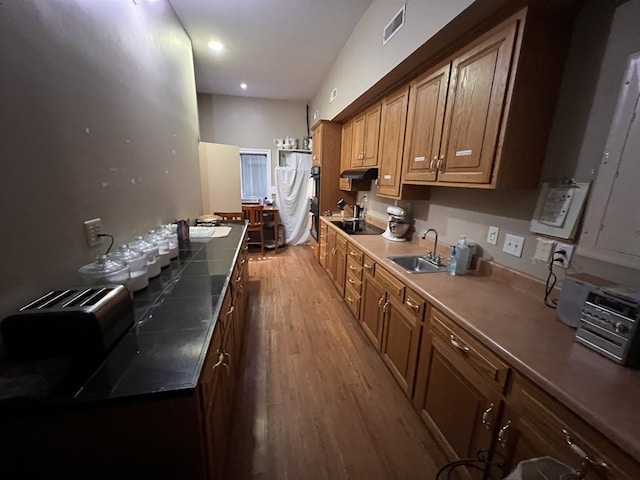 kitchen with black appliances, sink, and hardwood / wood-style floors