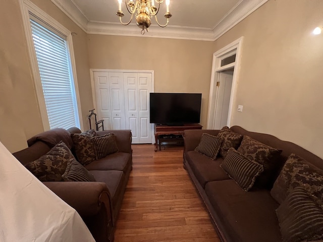 living room with a notable chandelier, ornamental molding, and hardwood / wood-style floors