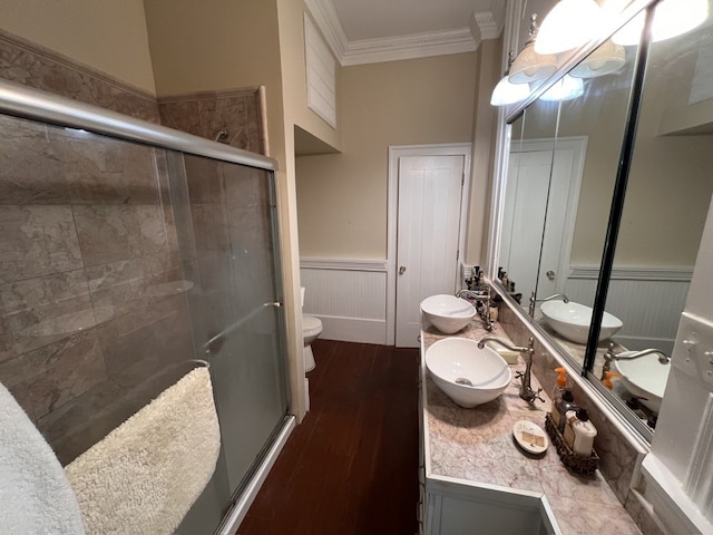 bathroom with toilet, crown molding, a shower with shower door, hardwood / wood-style floors, and vanity