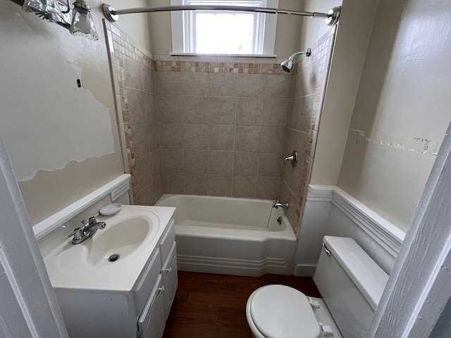 full bathroom featuring hardwood / wood-style flooring, tiled shower / bath combo, vanity, and toilet