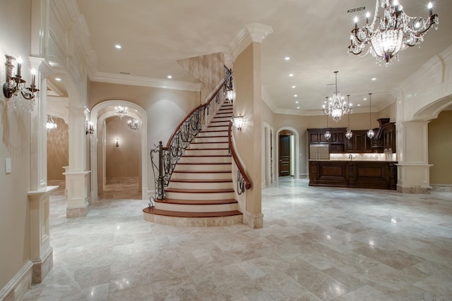 stairway with ornate columns, ornamental molding, light tile floors, and a chandelier