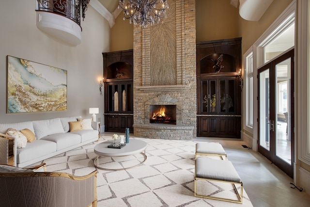 living room featuring a fireplace, a wealth of natural light, a towering ceiling, and a chandelier