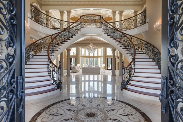 foyer entrance with tile floors, an inviting chandelier, and decorative columns