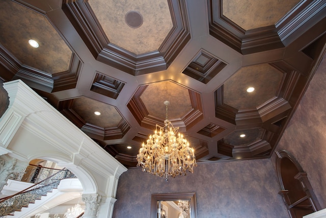 interior details featuring ornamental molding, coffered ceiling, ornate columns, and a chandelier