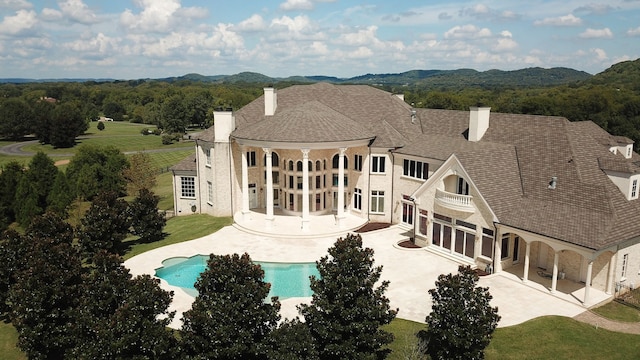 rear view of house featuring a balcony and a patio