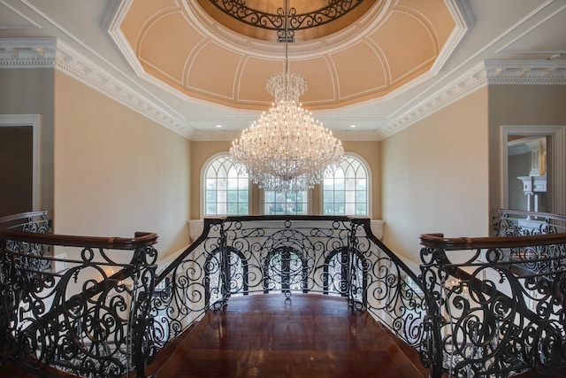 interior space with hardwood / wood-style floors, an inviting chandelier, a raised ceiling, and ornamental molding