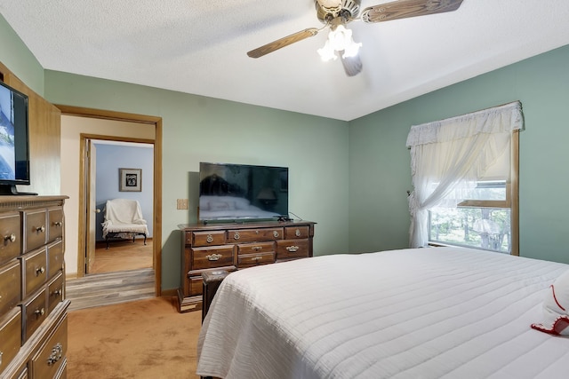 bedroom with light colored carpet, a textured ceiling, and ceiling fan