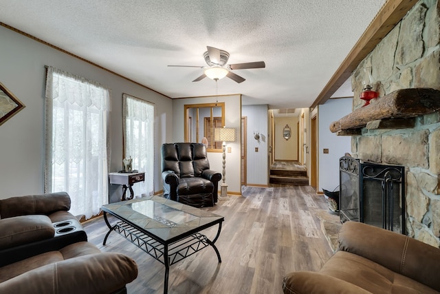 living room with a fireplace, ceiling fan, hardwood / wood-style flooring, and a textured ceiling