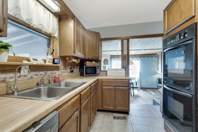 kitchen with kitchen peninsula, stainless steel appliances, tasteful backsplash, sink, and light tile floors