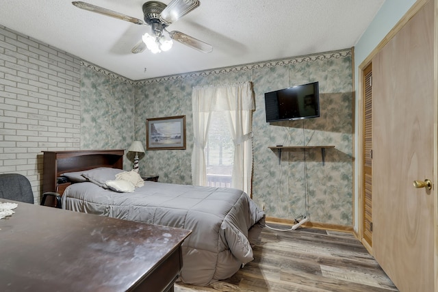 bedroom with ceiling fan, hardwood / wood-style flooring, and a textured ceiling