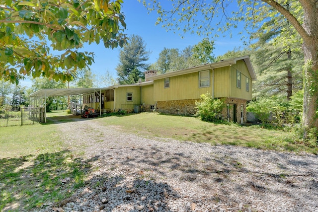 back of property featuring a carport, a yard, and central AC