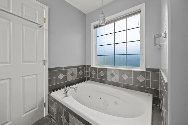 bathroom with a healthy amount of sunlight and tiled bath