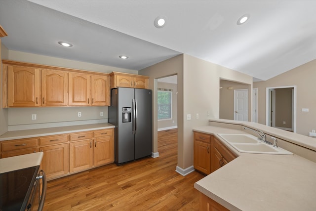 kitchen with light hardwood / wood-style floors, stove, lofted ceiling, stainless steel fridge, and sink