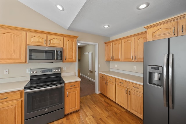 kitchen with appliances with stainless steel finishes, light hardwood / wood-style flooring, and vaulted ceiling