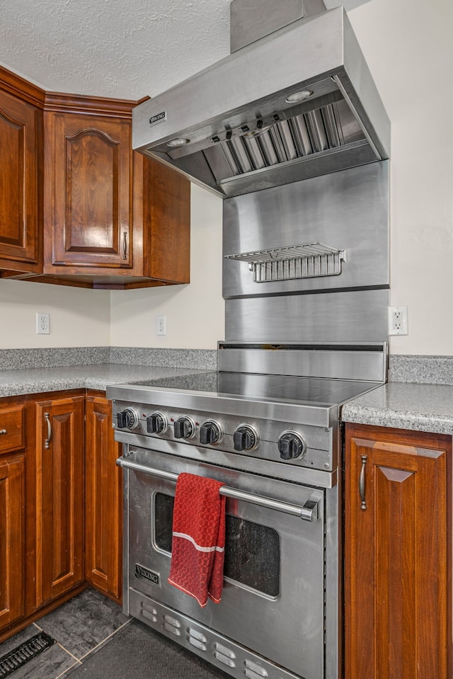 kitchen featuring high end stainless steel range, wall chimney exhaust hood, and a textured ceiling