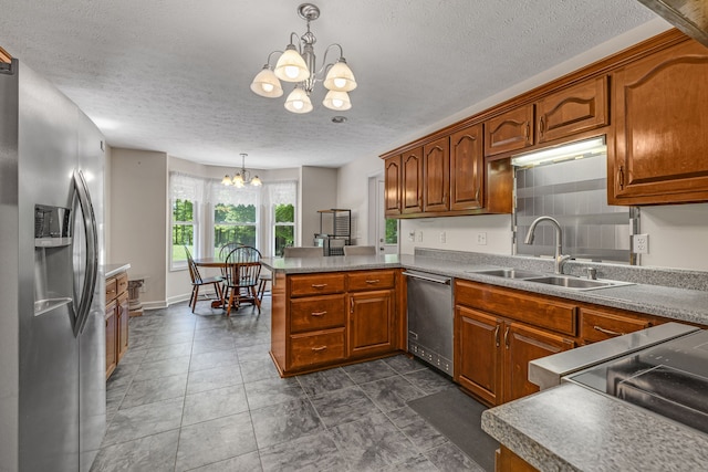 kitchen featuring sink, hanging light fixtures, a notable chandelier, kitchen peninsula, and stainless steel appliances