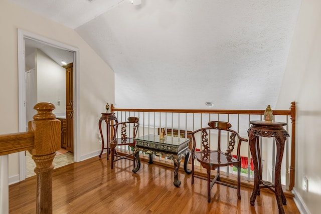 sitting room featuring a textured ceiling, hardwood / wood-style flooring, and vaulted ceiling