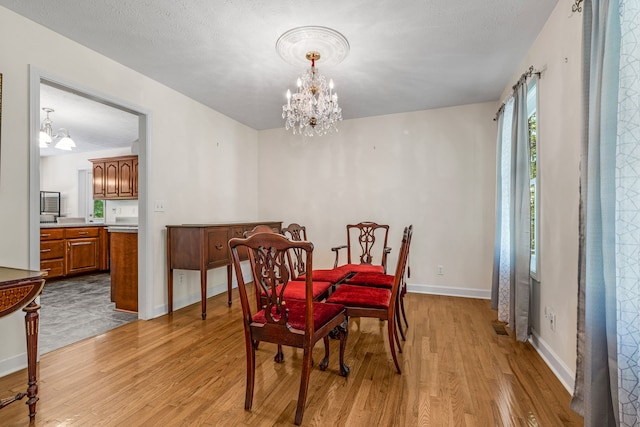 dining space featuring light hardwood / wood-style floors and a notable chandelier