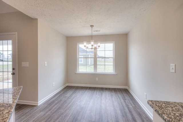 unfurnished dining area with a textured ceiling, dark hardwood / wood-style floors, and a notable chandelier