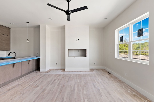 unfurnished living room featuring ceiling fan, light hardwood / wood-style flooring, and sink