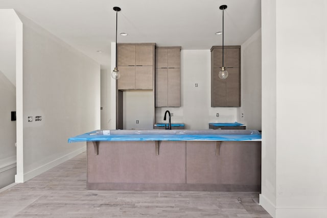 kitchen with a kitchen breakfast bar, light wood-type flooring, kitchen peninsula, and hanging light fixtures