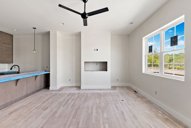 unfurnished living room with ceiling fan, light hardwood / wood-style flooring, and sink