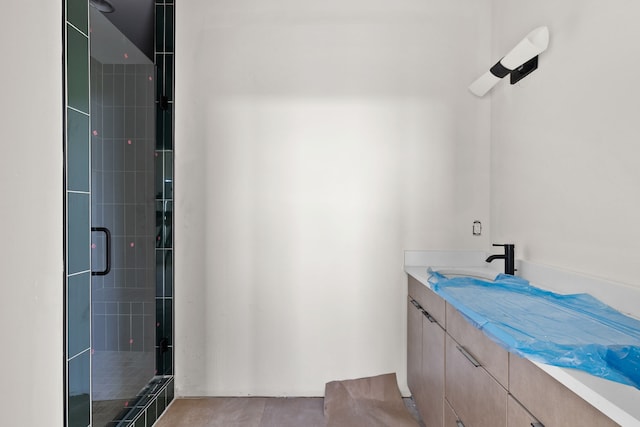 bathroom with a shower with shower door and vanity