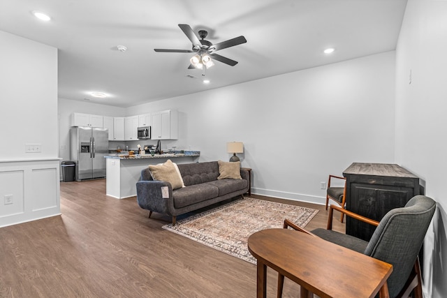 living area with a decorative wall, wood finished floors, a ceiling fan, and recessed lighting