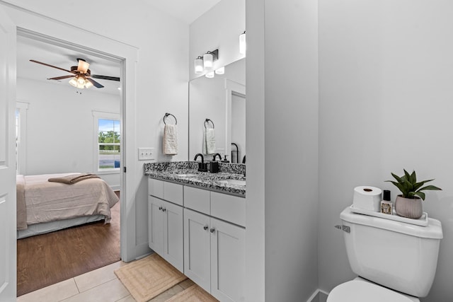 ensuite bathroom featuring connected bathroom, toilet, ceiling fan, tile patterned flooring, and vanity