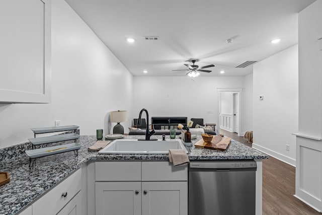 kitchen with visible vents, stainless steel dishwasher, a sink, dark stone counters, and a peninsula