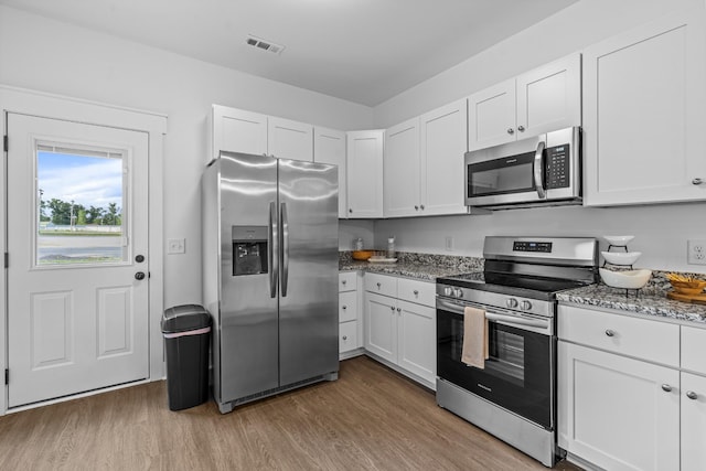 kitchen with stone counters, stainless steel appliances, wood finished floors, visible vents, and white cabinetry