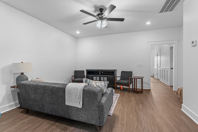 living room featuring ceiling fan, wood finished floors, visible vents, and baseboards