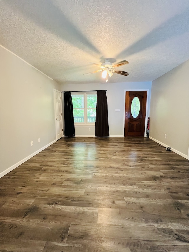 foyer entrance featuring ceiling fan, dark wood-type flooring, and a textured ceiling