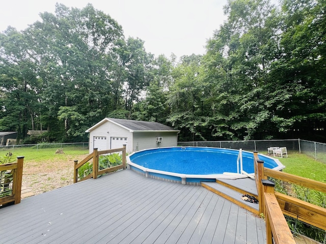 view of swimming pool featuring a garage, an outbuilding, a lawn, and a wooden deck