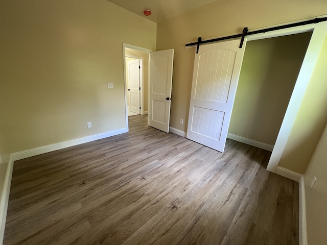 unfurnished bedroom with hardwood / wood-style floors and a barn door