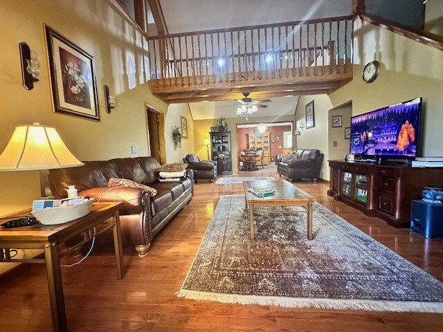 living room with ceiling fan, wood-type flooring, and a high ceiling