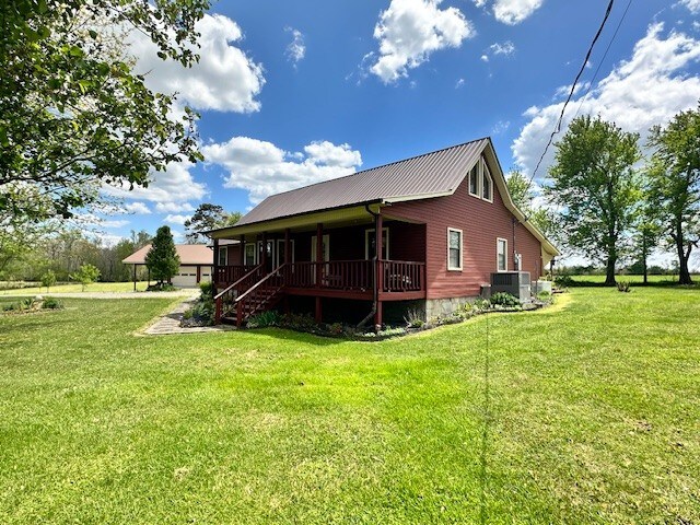 rear view of house with cooling unit and a lawn