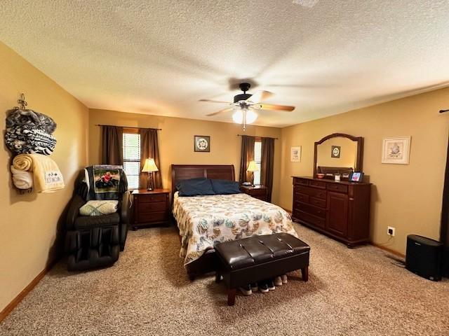 carpeted bedroom with ceiling fan and a textured ceiling