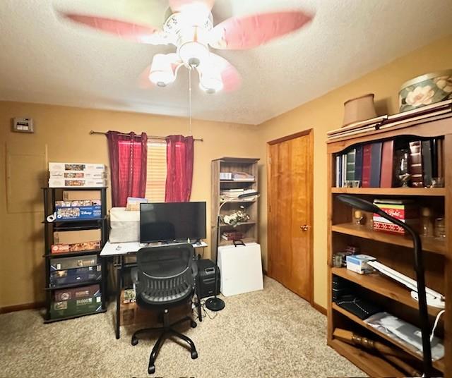 carpeted office space featuring a textured ceiling and ceiling fan