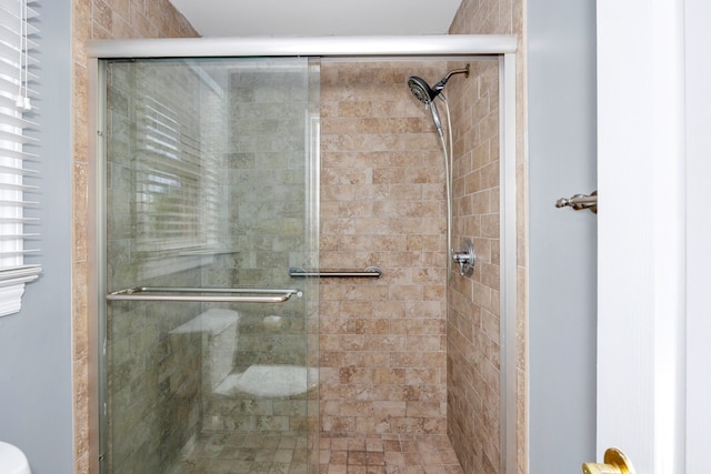 bathroom with a shower with door and toilet