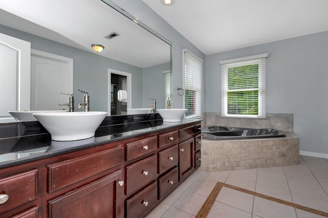 bathroom with tiled tub, tile floors, and dual bowl vanity