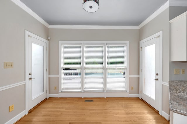 doorway with a healthy amount of sunlight, light hardwood / wood-style flooring, and crown molding