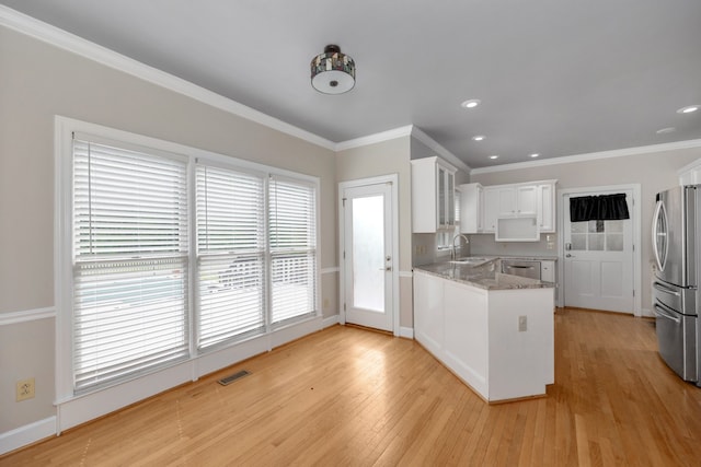 kitchen with kitchen peninsula, light hardwood / wood-style flooring, white cabinets, sink, and ornamental molding