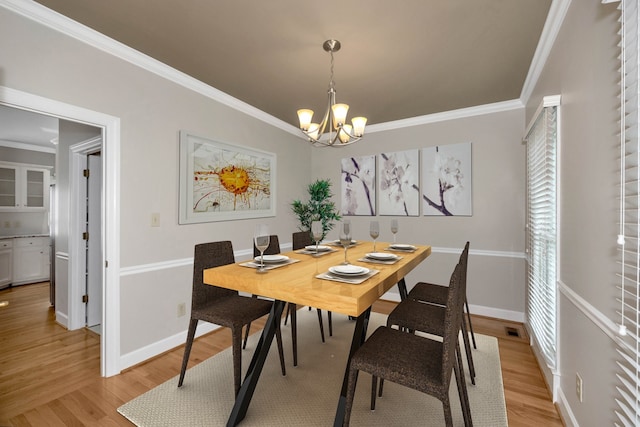 dining area with light wood-type flooring, a chandelier, and ornamental molding