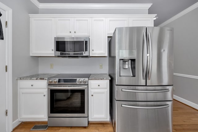 kitchen featuring light stone countertops, appliances with stainless steel finishes, light hardwood / wood-style floors, white cabinets, and ornamental molding