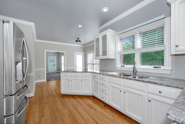 kitchen with crown molding, stainless steel refrigerator with ice dispenser, white cabinets, sink, and light wood-type flooring