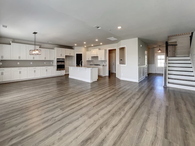 unfurnished living room with hardwood / wood-style floors, sink, and an inviting chandelier