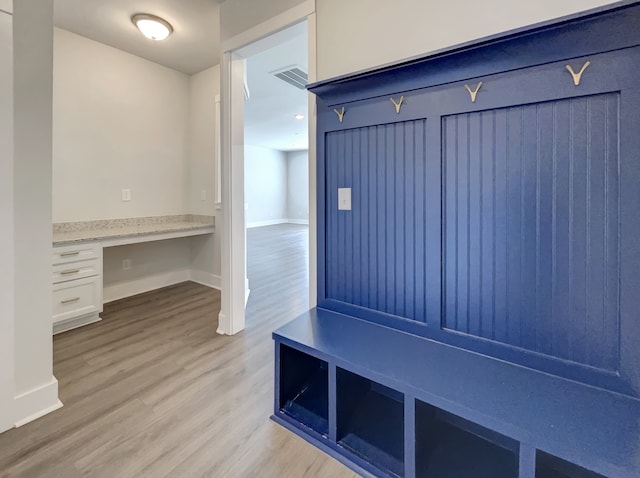 mudroom with built in desk and light hardwood / wood-style floors